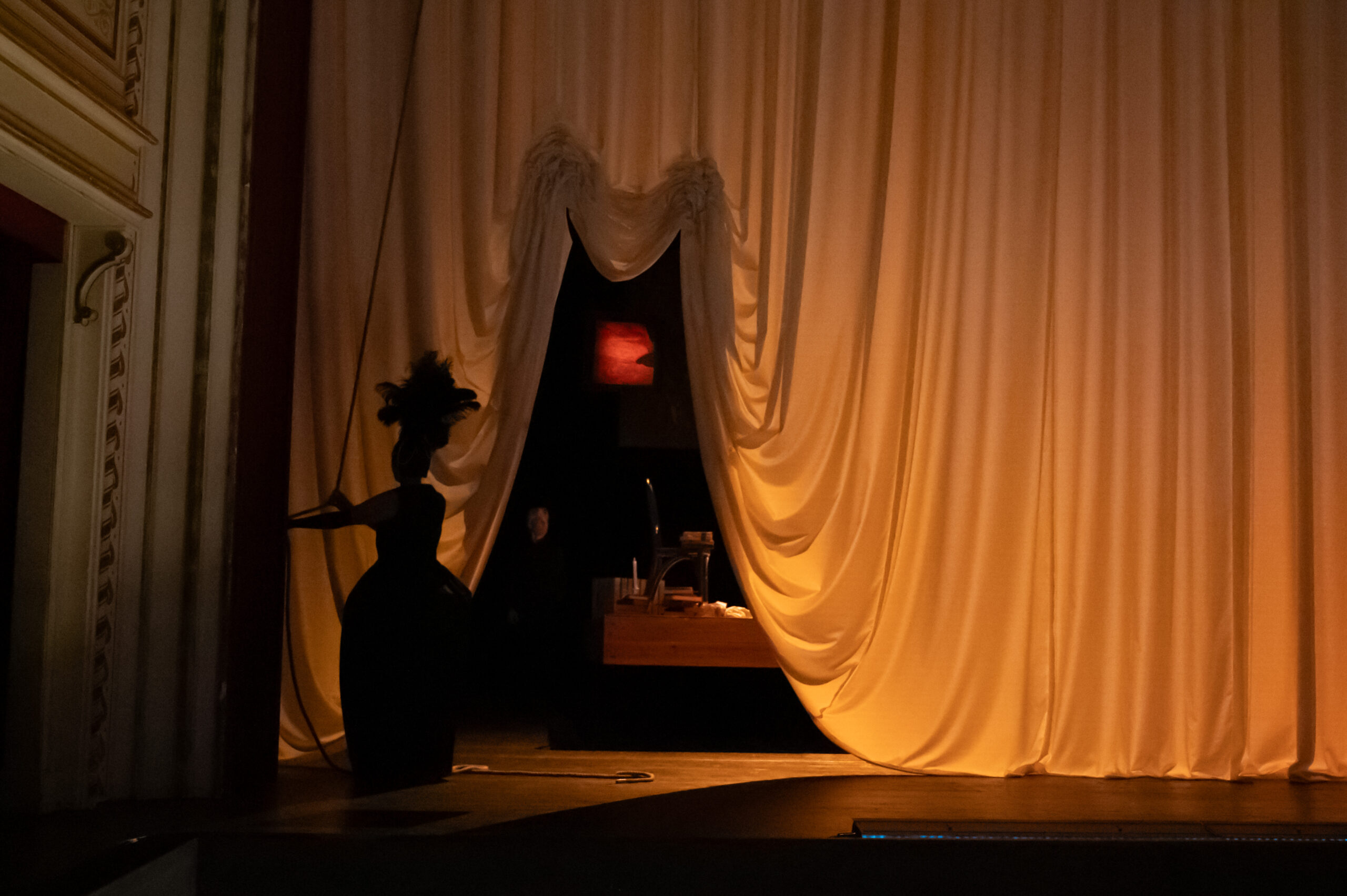 Bühnenbild und Kostüm von Lisa Behensky für La Bohème – große Vorhangöffnung mit silhouettierter Figur und Einblick in einen Innenraum