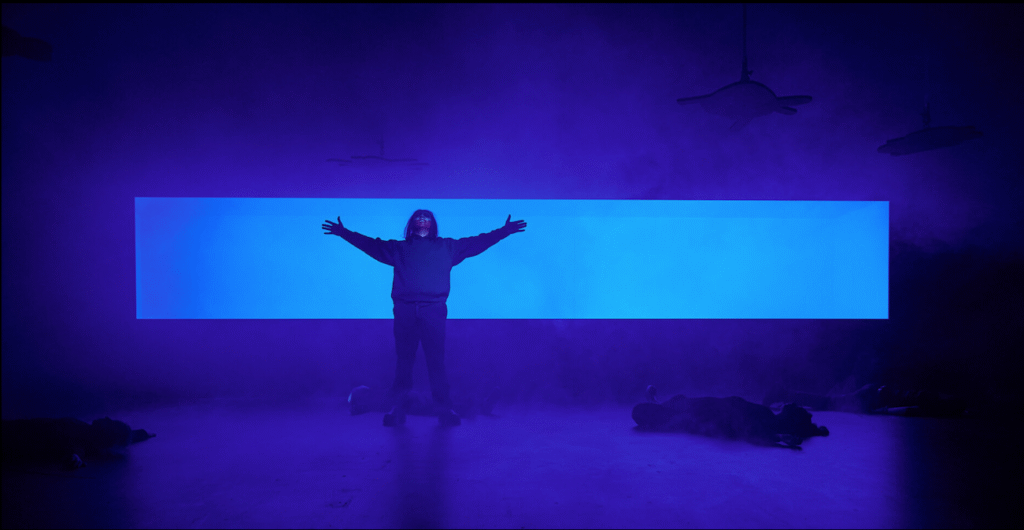 Szenografie und Kostüm von Lisa Behensky für ICARO – zentrale Figur vor horizontalem Lichtraum im nebligen Bühnenbild mit liegenden und hängenden Körpern