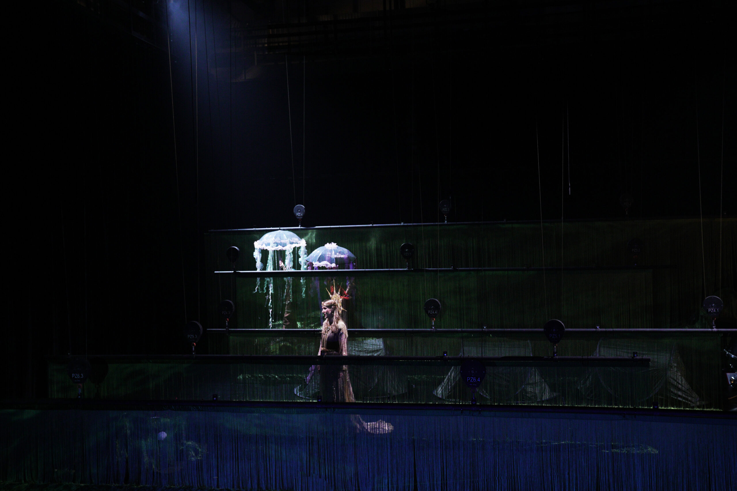 Bühnenbild und Kostüm von Lisa Behensky für Oberon / Träume – mehrschichtiger Bühnenraum aus Fadenvorhängen mit Quallenschirmen und zentraler traumhafter Figur