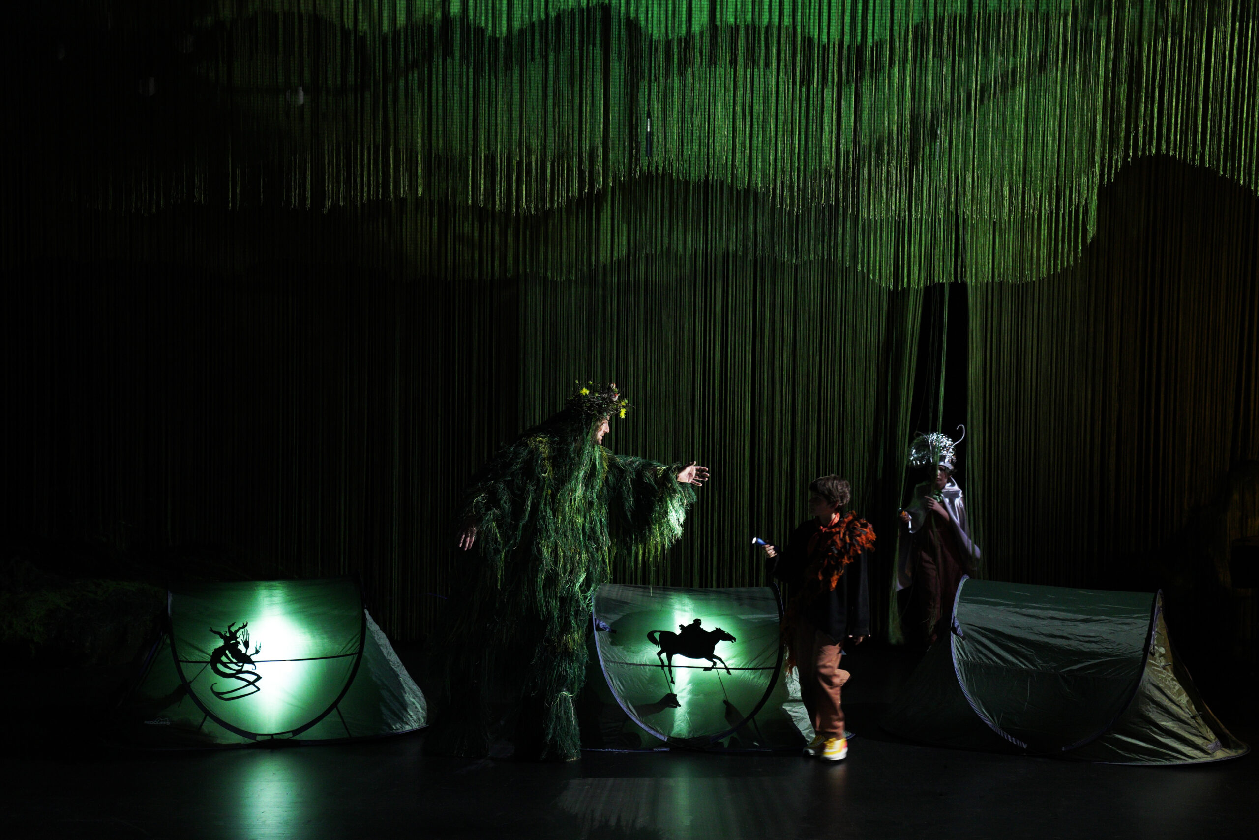 Bühnenbild und Kostüm von Lisa Behensky für Oberon / Träume – grüne, organische Figur und Kind im dichten Fadenraum Zelt Schattenspiel